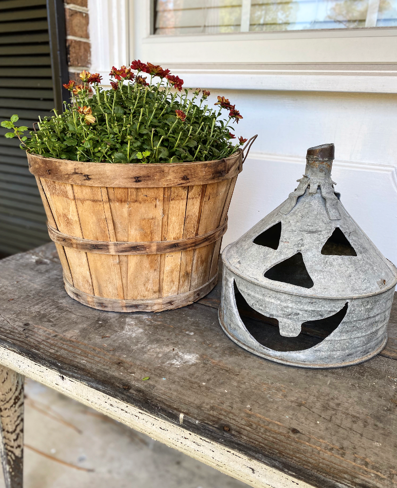 Funnel Jack O lantern next to an apple basket filled with mums